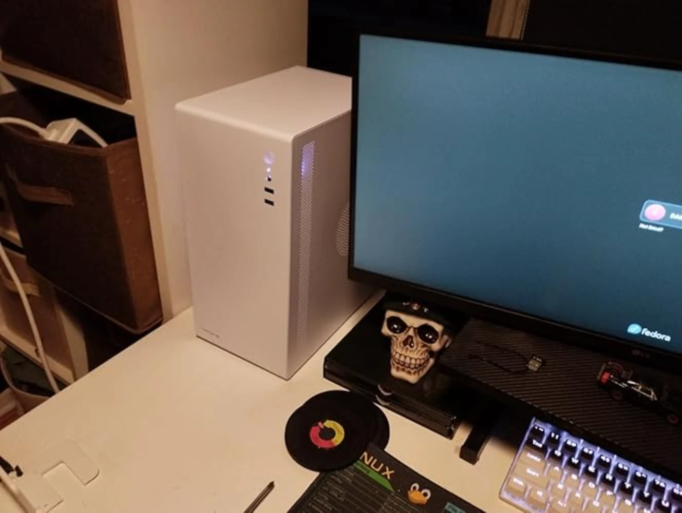 Moderner PC-Arbeitsplatz mit Monitor, weißem Desktop-PC und Tastatur auf aufgeräumtem Schreibtisch.