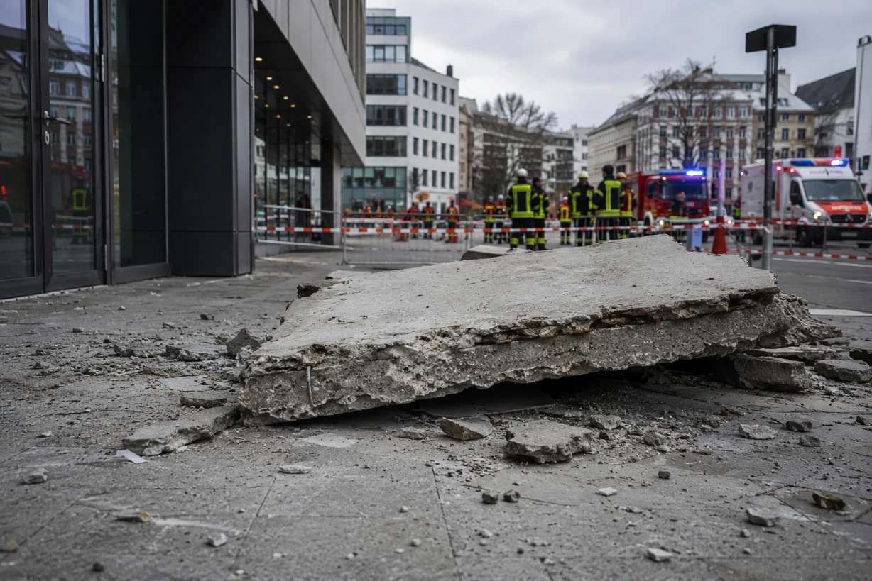 Betonplatte auf Gehweg, Einsatzkräfte sichern Unfallstelle vor modernem Gebäude in Köln