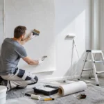 DIY Raufasertapete: Heimwerker bringt Tapete an und streicht Wand in hellem skandinavischem Raum Raum hel.