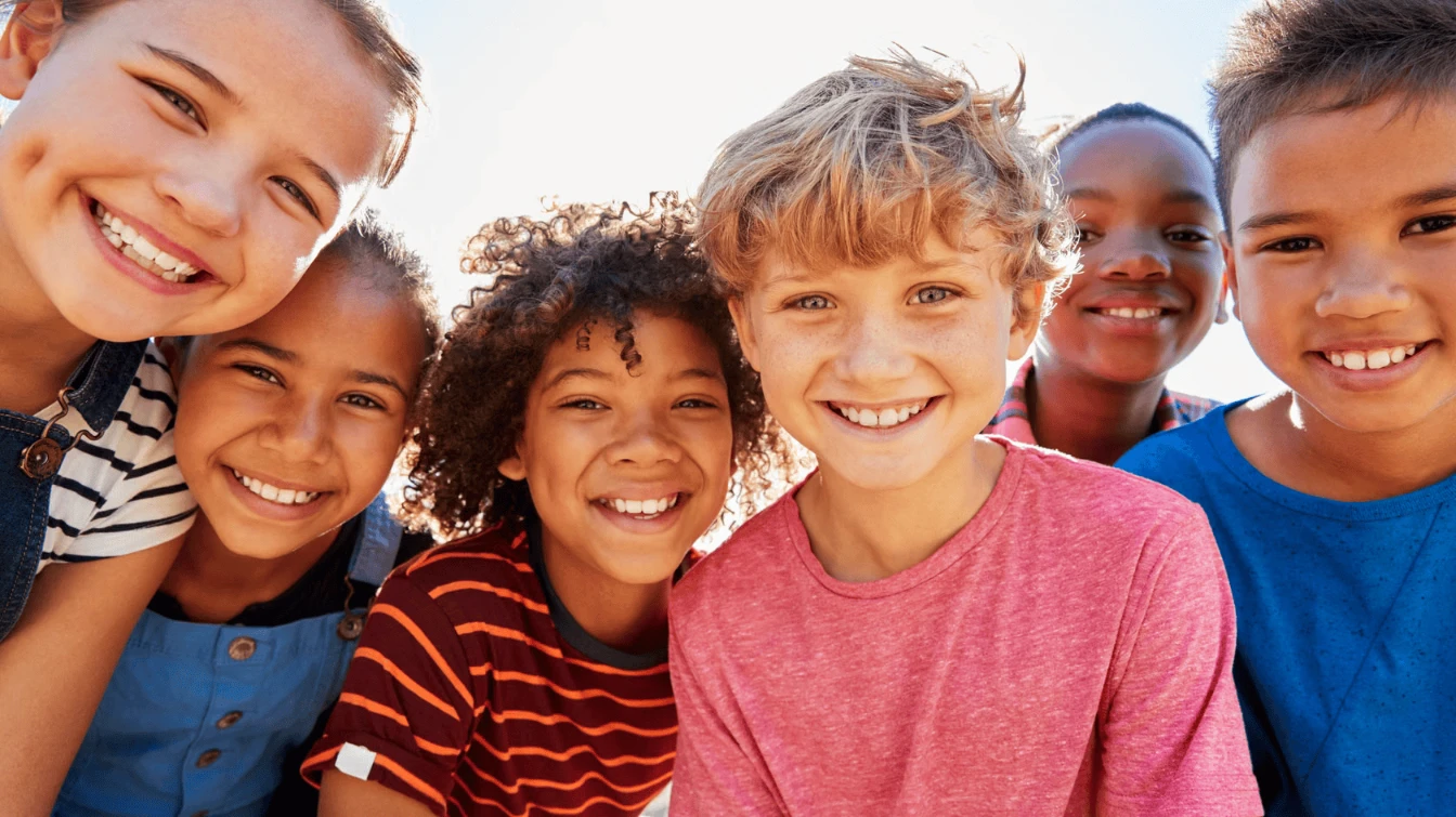Lächelnde Kinder im Freien zeigen Freude, Zusammenhalt und die unbeschwerte Zeit der Kindheit.